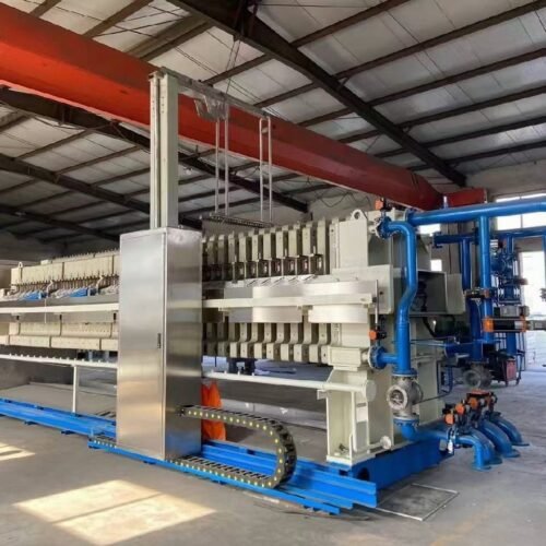 Industrial membrane filter press in a factory workshop, showing hydraulic cylinders, filter plates and control panel.